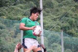 緑色のジャージを着たラグビー選手が、他の選手に持ち上げられ、高くジャンプしてボールをキャッチしている瞬間