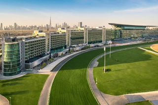 ドバイの広大な競馬場と豪華なホテルが写っており、背景にはブルジュ・ハリファを含む高層ビル群が広がる都市のスカイラインが見えます。