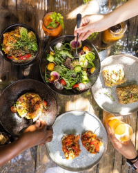 木製のテーブルを囲んで複数の人がヘルシーな食事を楽しんでいる様子を上から撮影した写真です